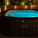 Lay-Z-Spa Maldives inflatable hot tub glowing with blue LED lighting outdoors in the evening.