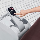 Hand using the digital control panel on a Lay-Z-Spa Maldives inflatable hot tub to adjust temperature and settings.