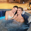 Couple relaxing together in a bubbling inflatable hot tub with padded headrests and warm lighting.