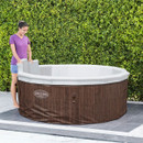 Woman installing or adjusting the interior liner of a Lay-Z-Spa Toronto hot tub outdoors.