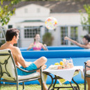 People relaxing in a garden beside an Intex Easy Set inflatable pool with drinks on a table