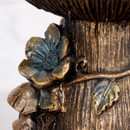 Close-up detail of the bronze-effect base of the fairy fountain, featuring a decorative flower and leaf accents.