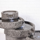 Angled view of the tiered grey stone-effect water feature showing multiple bowls with water cascading between them.