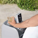 Lay-Z-Spa control panel and pump unit with integrated cup holder, holding a drink beside the inflatable hot tub.