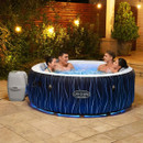 Four adults enjoying a Lay-Z-Spa Hollywood inflatable hot tub outdoors with blue LED lighting in a garden setting.