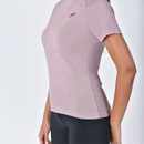 Side view of woman wearing a mauve WeatherBeeta short sleeve half zip riding top with black leggings.