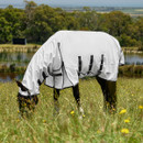 Horse grazing wearing white full neck fly rug with black straps in meadow