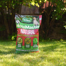 Bag of MossMaster Natural moss remover on green grass, featuring text: "Child & Pet Friendly," under sunlight with a background of trees.
