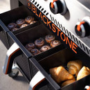 Close-up of Blackstone griddle warming drawers holding cinnamon rolls and croissants beneath illuminated control knobs.