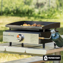 Blackstone portable tabletop griddle on picnic table with propane-ready label and outdoor background
