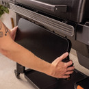 Removable front storage panel being installed on Traeger pellet grill base frame.