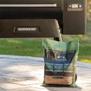 Traeger Mesquite hardwood pellets bag beside Traeger Ironwood 885 pellet grill outdoors