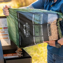 Person pouring Traeger Mesquite wood pellets into a Traeger pellet grill hopper