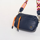 Close-up of the navy leather crossbody bag showing twin front zips with bright orange pull cords and gold-tone hardware.