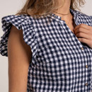 Close-up of navy and white gingham fabric highlighting the frilled shoulder detail and lightweight textured finish.