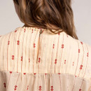 Close-up of back neckline with keyhole button fastening and pintuck detail on cream embroidered blouse.
