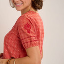 Close-up side view highlighting the short puff sleeve with embroidered floral detail and decorative stitched bands above the cuff.