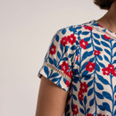 Close-up of the short sleeve showing blue leaf and red floral print with ladder trim insert detail.