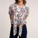 Detail of the tie neck bow on the cream paisley print blouse, paired with dark indigo jeans.