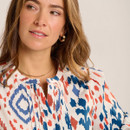 Close-up of the cream abstract print blouse showing notch neckline and pleated front detail.