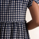 Close-up detail of the navy and white gingham fabric with gathered waist seam and subtle textured finish.