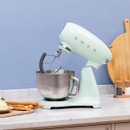 Pastel green SMEG stand mixer on kitchen worktop with stainless steel bowl and paddle attachment