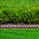 Rust-finish decorative landscape edging with a repeating wave pattern, separating a gravel bed and lawn in front of a trimmed hedge.