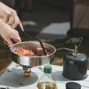 Close-up of frying pan cooking vegetables on portable camping stove