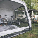 Camping awning tent attached to campervan with bicycle stored inside