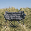 Outwell double camping sofa set up on grass dunes in outdoor setting
