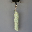 A braided light green rope hangs from a simple black cord and gold clip against a gray wall. The scene conveys simplicity and minimalism.