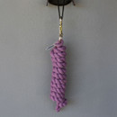 A thick, braided pink rope hangs vertically on a wall from a black cord and metal clip, conveying simplicity and utility.