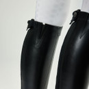 Close-up of sleek black leather riding boots, with white textured leggings visible above. The image conveys a sense of style and sophistication.