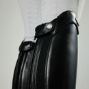 Close-up of a person wearing sleek black leather riding boots with intricate stitching, paired with white breeches, conveying elegance and sophistication.