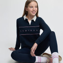 Teen girl in a navy long-sleeve shirt with "LeMieux" logo, sitting cross-legged. She smiles, creating a relaxed, cheerful atmosphere.