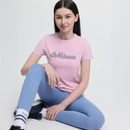 Young woman sitting against a plain backdrop, wearing a pink "LeMieux" T-shirt and light blue leggings. She appears relaxed and confident.