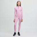 A young woman in a light pink athletic bodysuit smiles confidently in a minimalist studio. She wears black sneakers, conveying a modern, sporty vibe.