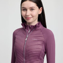 Young woman wearing a mauve LeMieux jacket, smiling softly. The jacket features a quilted design with a high collar, conveying a sense of warmth and style.