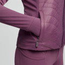 Close-up of a person wearing a purple quilted jacket with an arm inserted in a side pocket. The matching leggings create a sleek, coordinated look.