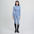 Young woman in a fitted light blue outfit and black knee-high boots, standing against a plain background. She appears confident and poised.