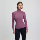 A woman in a fitted mauve long-sleeve top with a high collar and zipper stands against a plain grey background, conveying a sleek, athletic style.