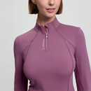 A woman in a fitted, mauve long-sleeve top with a partial zipper and "LeMieux" logo poses confidently. The mood is stylish and modern.