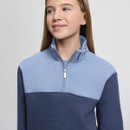 Young person wearing a light and dark blue pullover with a quarter zipper. They are smiling softly, looking slightly to the side. Neutral background.