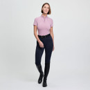 A woman in a pink short-sleeve top and navy leggings stands confidently. She wears black knee-high boots and a belt, set against a plain grey background.