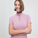 A smiling person with a bob haircut wears a light purple, short-sleeve top with a zipper and folded arms, conveying a relaxed and confident mood.