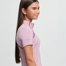 Young woman in profile wearing a light pink, short-sleeve athletic top with "LeMieux" logo on the sleeve. She has long, straight hair and a gentle smile.