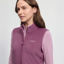A woman wearing a purple LeMieux vest over a light pink top stands against a plain background. She looks calmly to the side, conveying a serene mood.