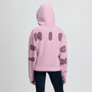 Person in a pink hooded sweatshirt with large, dark pink bubble letters reading "LEMIEUX" on the back. They wear dark leggings, creating a casual look.