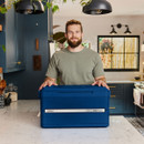 Man standing in a modern kitchen with a closed Coleman Snap ’N’ Go cooler on a marble worktop.