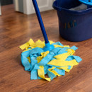 Close-up of a Flash mop with blue handle and yellow and blue microfiber mop head on a wooden floor, with a blue bucket of soapy water in the background.